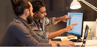 Team members reviewing work on a computer